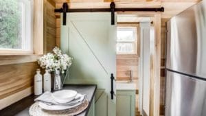 Bathroom vanity separated from the rest of the bathroom by a mint sliding barn door.