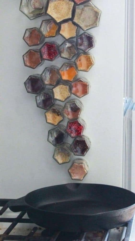 Spice jars mounted on the wall in hexagonal containers.