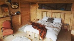 Bed in a tiny home with wood paneling around it.