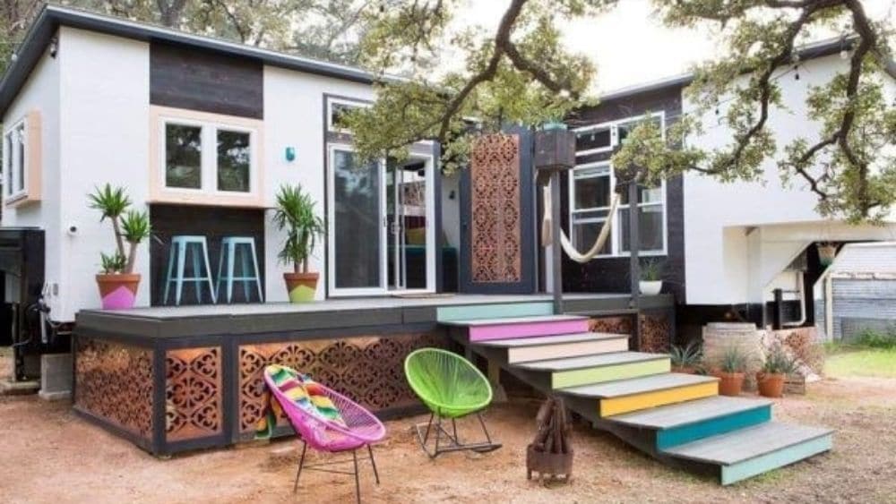 A tiny home with a large entertainment space and steps leading into the yard.