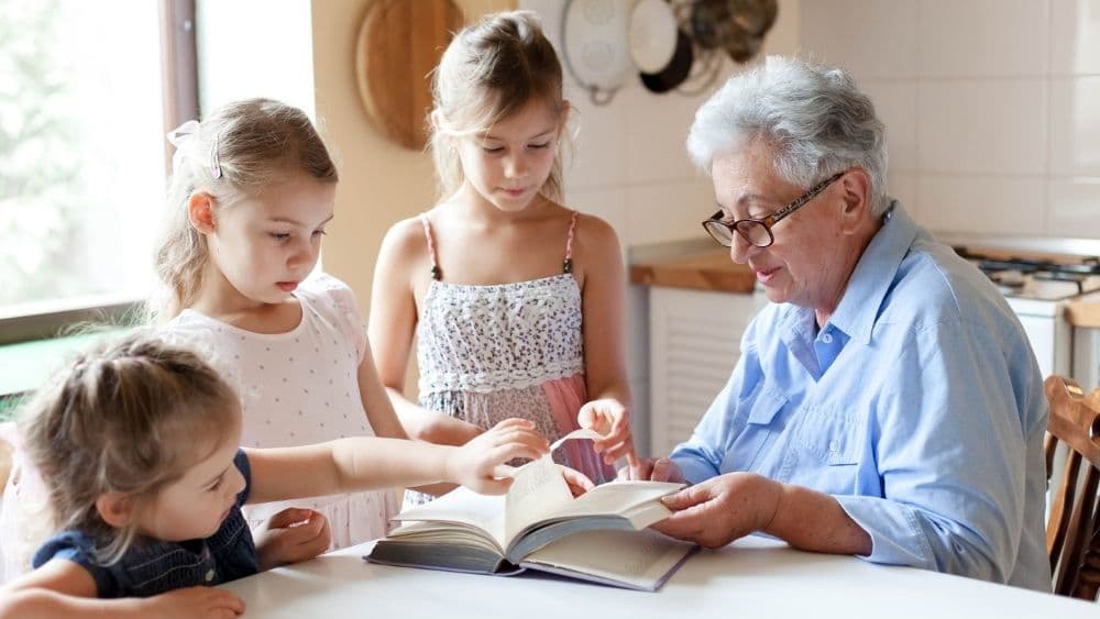 Grandkids gathered around a book with their grandparent.