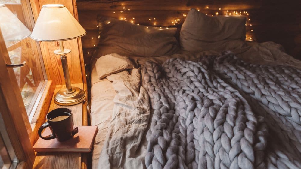 Cozy bedroom with twinkle lights and a thick knitted blanket.