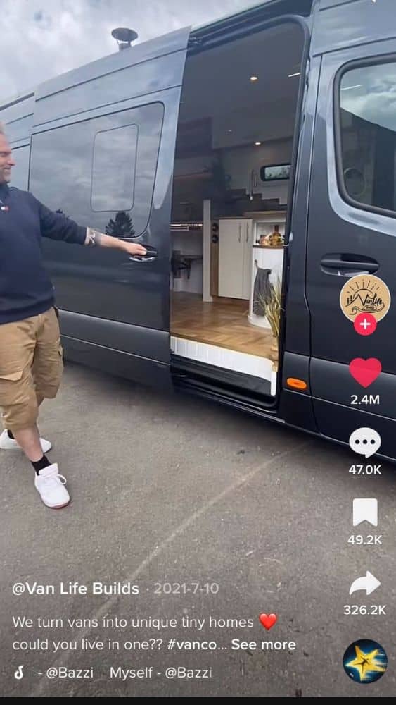Screenshot of @Van Life Builds' video showing a cargo van door sliding open to reveal a tiny home inside.