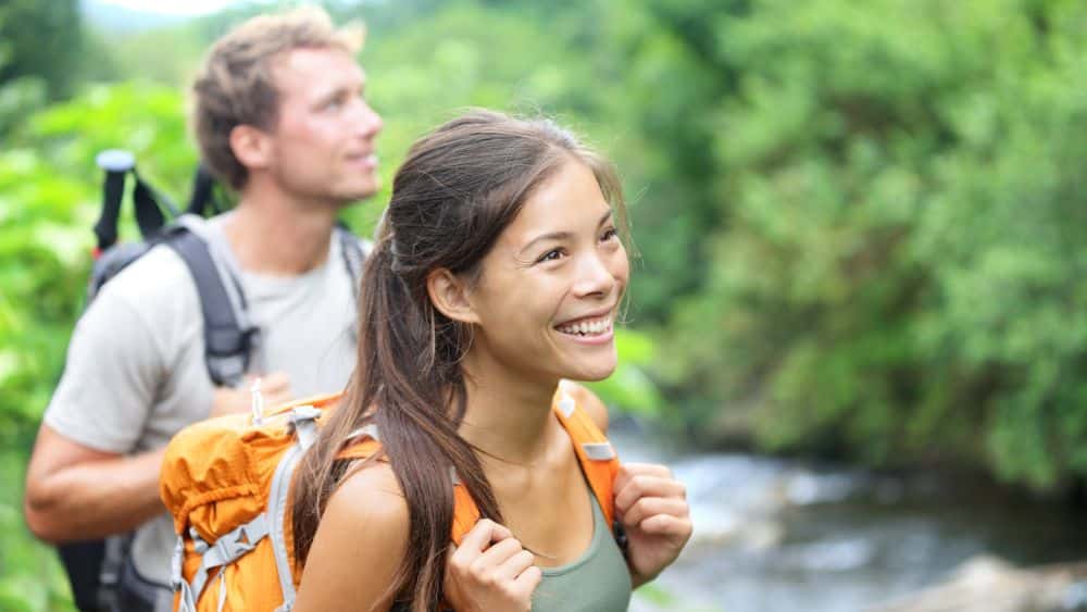 Two people hiking and smiling as they look around at the greenery.